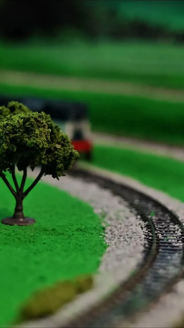 Composição de trem em miniatura sobre trilhos detalhados